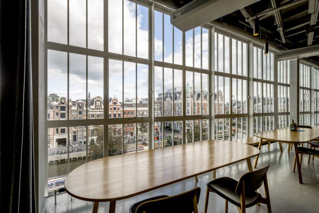 Modern ingerichte ruimte met grote ramen, met uitzicht op de historische gevels aan de Sint Jorissteeg in Amsterdam.